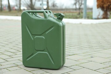 One khaki metal canister on pavement outdoors, space for text