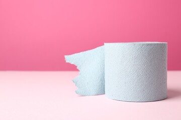 Blue toilet paper roll on pink background. Space for text