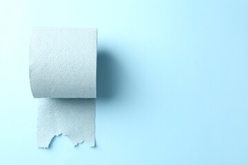 Color toilet paper roll on light blue background, top view. Space for text