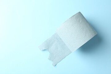 Color toilet paper roll on light blue background, top view. Space for text