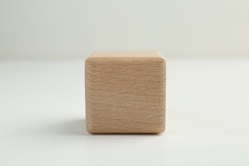 One blank wooden cube on white table, closeup