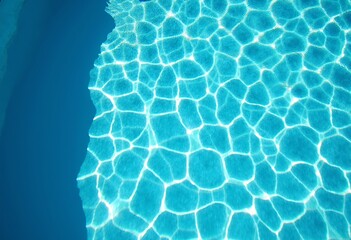 Obraz premium Summer Serenity: Top-Down View of a Blue-Toned Swimming Pool with Clear, Rippling Water Sparkling Under Sunlight, Evoking a Vibrant and Lush Landscape on a Bright Day.