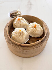 steamed Xiao long bao Shanghai small meat dumpling in bamboo basket with ginger vinegar sauce on white table chinese dim sum menu banquet restaurant halal food