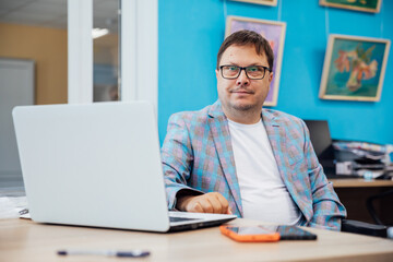Fototapeta premium Portrait of a young businessman working in the office at a laptop and holding a book.