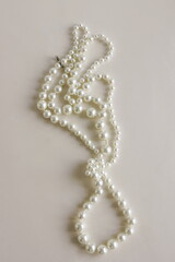 Elegant pearl necklace on beige background top view close up. Fashion background