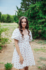 Fototapeta premium Beautiful brunette woman in summer dress walking in the park