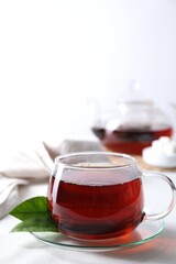 Refreshing black tea in cup on light table. Space for text