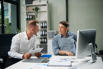 Obraz premium Two business workers talking on the smartphone and using laptop