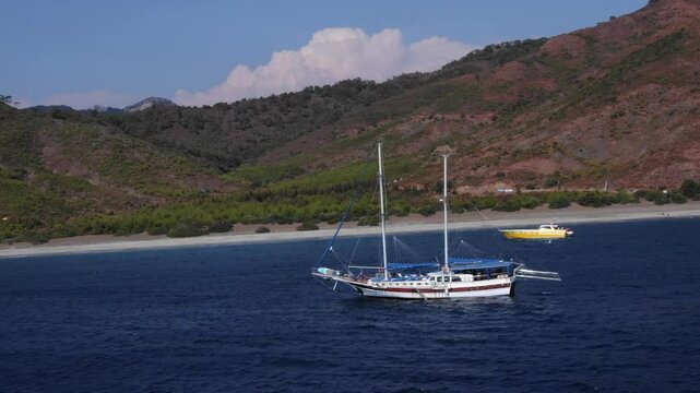 Typical Turkish sailing vessel, gulet on deep blue waters, surrounded by scenic mountains, Karaincir beach, Turkey. Aerial lateral view
