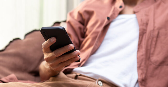 close up man hand using smartphone during sitting on chair at home or cafe