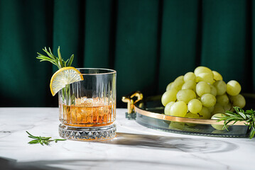 a glass of whiskey decorated with lemon and rosemary