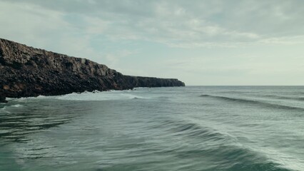 Sea waves wash the rocky mountains on the coast, a bird's-eye view from the sea