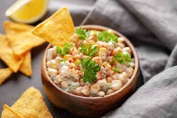 Mexican street corn dip in bowl. Elote dip with nachos chips. Latin American cuisine