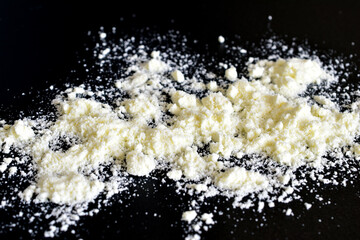 White dry milk is scattered on a black background.