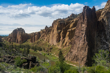 Fototapeta premium The image showcases the stunning formations of rock cliffs along a tranquil river, highlighting the natural beauty found in Oregon's breathtaking landscapes.