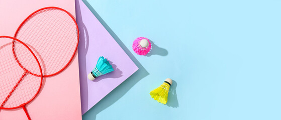 Badminton rackets and shuttlecocks on color background
