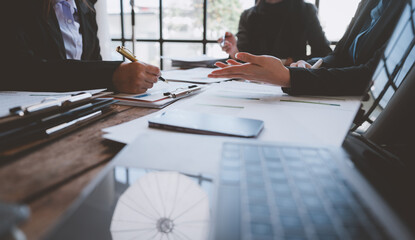 Businesswomen engaging in a discussion and taking notes during a corporate meeting, analyzing reports and collaborating effectively in the office environment