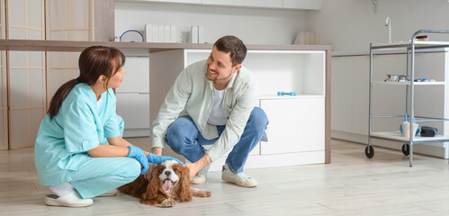 Female Asian veterinarian with owner and cute dog in clinic