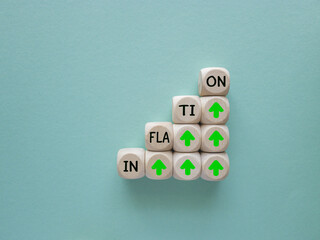 Inflation wording on wooden cube block with green up arrow for increasing of inflation and economic recession after covid-19 pandemic and Russia Ukraine war concept. Blue background.