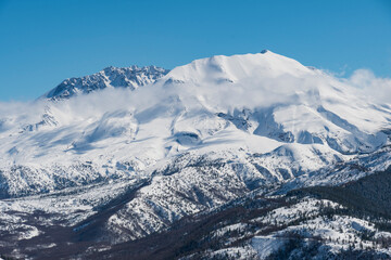 A breathtaking view of towering snow-coated mountains stretches under a clear azure sky, showcasing the majestic beauty of nature and inviting outdoor enthusiasts.