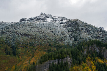 This stunning mountain landscape reveals a snowy peak amidst lush green slopes, capturing the beauty and majesty of nature under a moody sky.