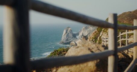 Panoramic view of the sea washing the rocky shores and ledges. View from the top of the mountain from the observation deck through the fence