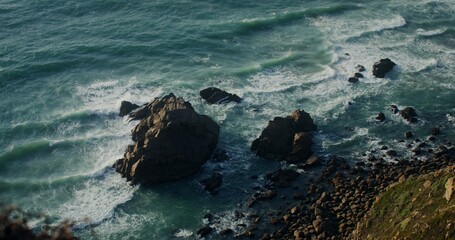 Top view of the rocky seashore, sea waves beating the rocks