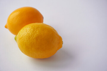 Close-up of vibrant yellow lemons with smooth, glossy peels, showcasing their fresh texture and natural appeal on a clean background.