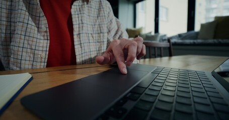 A woman in everyday ojeda uses a laptop while sitting at a table. She runs her finger over the...