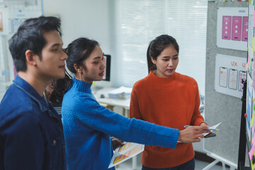 Web designers working together in the office reviewing mobile application interface designs on a...