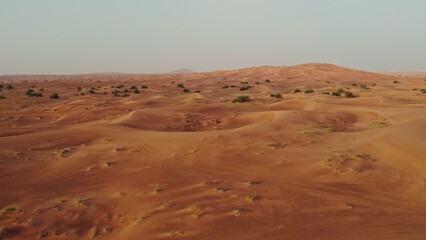Drone view of a lifeless desert with sparse vegetation and off-road cars