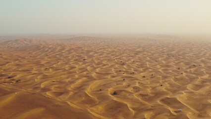 Obraz premium Drone view of sand dunes with sand merging with the sky. Driving off-road in a lifeless desert