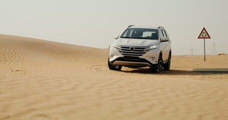 Obraz premium A white car is standing among sand dunes in the desert, there are no people