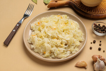 Plate of tasty sauerkraut with spices and garlic on beige background