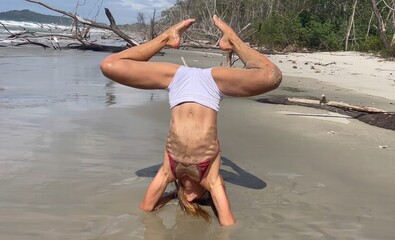 Young woman doing yoga on the beach.