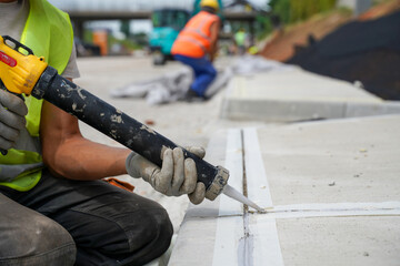 Close-up of filling gaps between road curbs and concrete highway for a secure seal