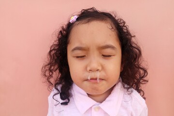 Asian female toddler having a bad cold with snot coming out of her nose, close up view.