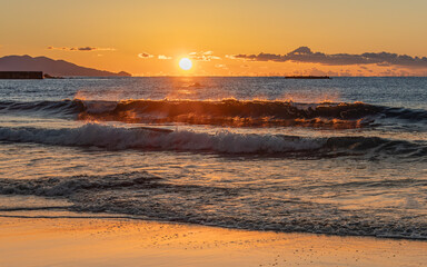朝日に染まる波と砂浜
