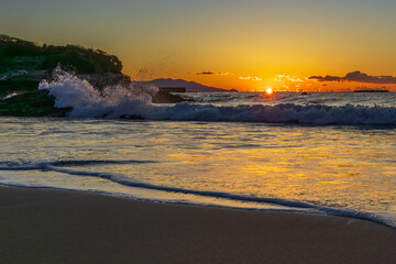 朝日に染まる波と砂浜