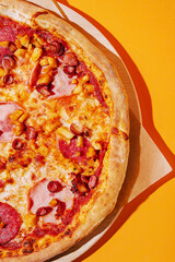 Colorful pizza topped with meats and vegetables on vibrant background