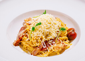 Delicious spaghetti dish with cheese and bacon on a white plate