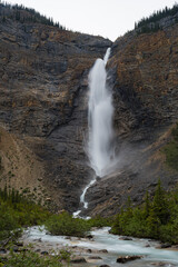 A powerful waterfall thundering down rocky cliffs surrounded by lush greenery, symbolizing the untamed beauty of nature and the spirit of adventure that beckons travelers.