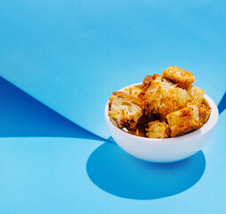 Crunchy croutons in a white bowl against a blue background
