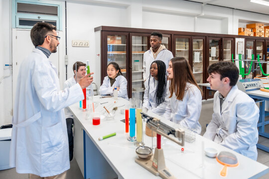 Chemistry teacher explaining experiment to students in university laboratory - Powered by Adobe