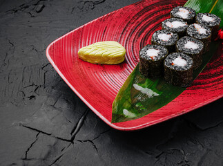 Sushi rolls served on a vibrant plate with wasabi garnish