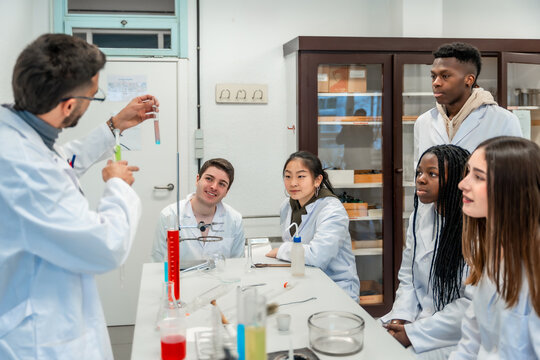 Chemistry teacher showing test tube to students in university lab