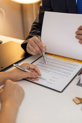 Fototapeta premium A man and a woman are signing a contract for a house. The man is holding a pen and the woman is holding a house model 