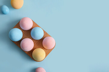 Wooden holder with painted Easter eggs on blue background