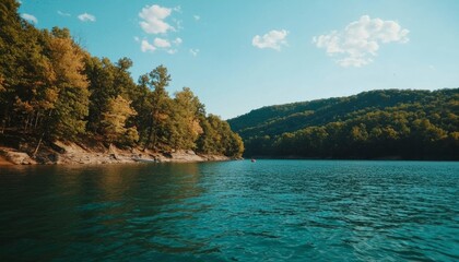 Obraz premium Lake landscape with forests on hills and a blue sky with clouds ideal for travel