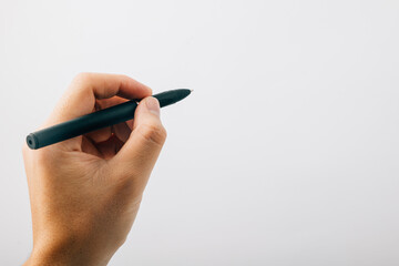 A person hand is holding a pen and writing on a white background. Concept of creativity and the act of putting thoughts into words. Scene is focused and determined